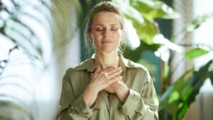 Femme, mains jointent sur le haut du thorax, elle est dans un état de centration. Comme en méditation